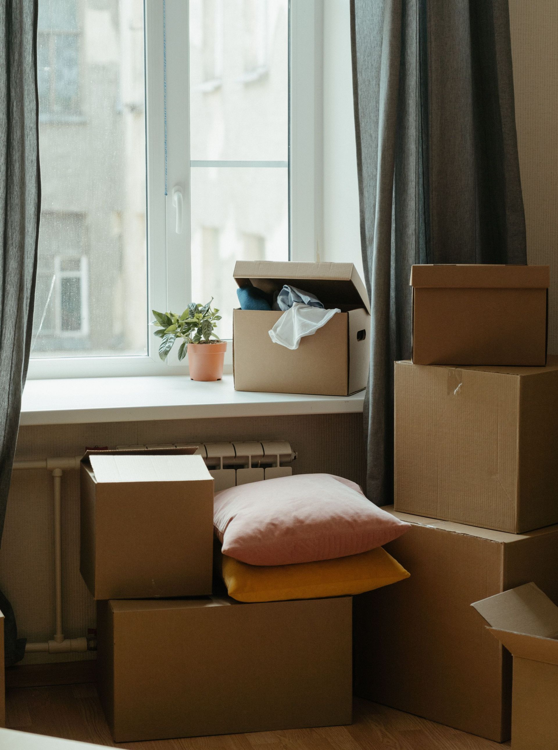 Stack of moving boxes in a sunlit room, symbolizing a fresh start in a new apartment.