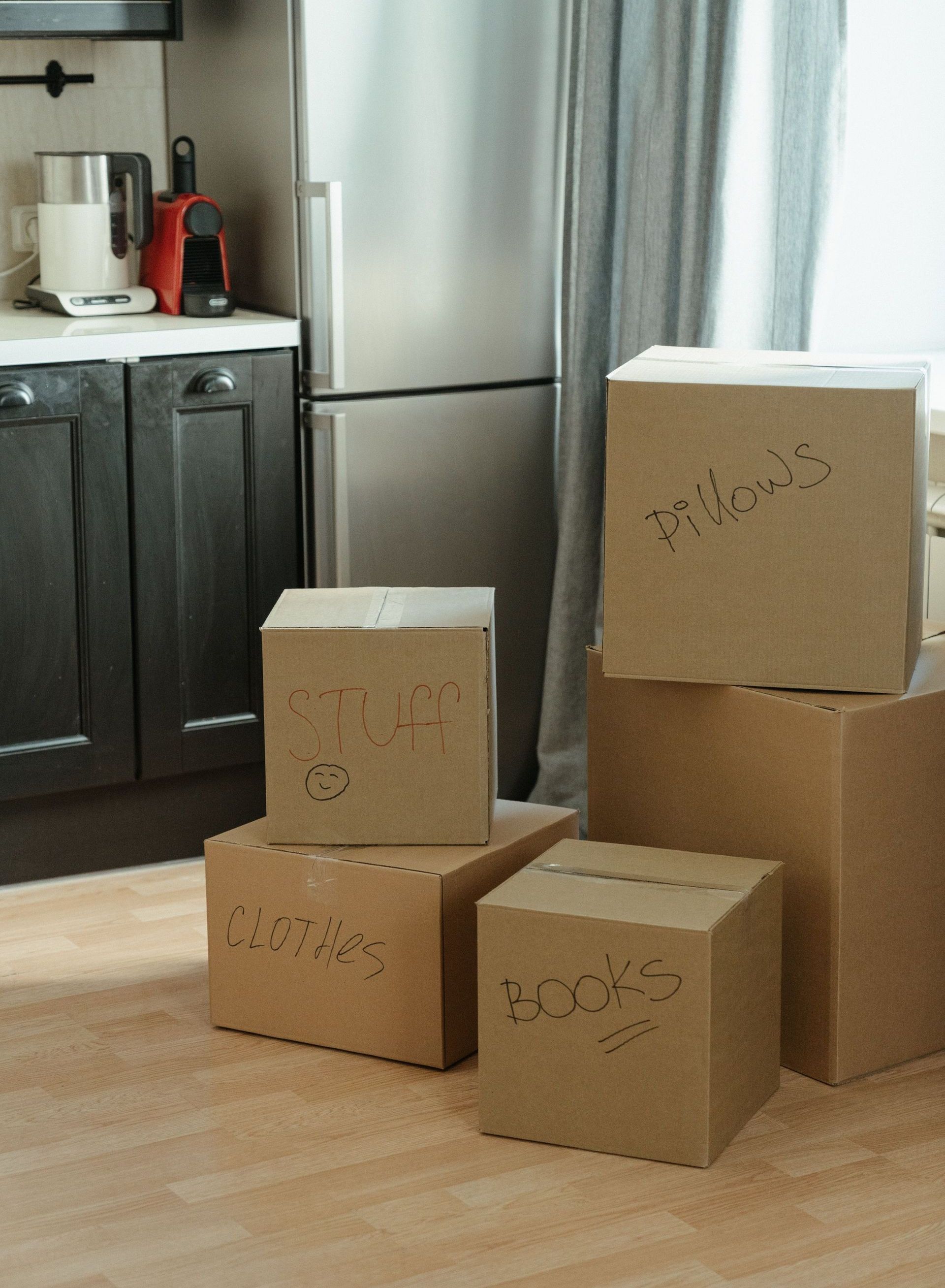 Cardboard boxes labeled with contents in a kitchen, suggesting a recent move-in.